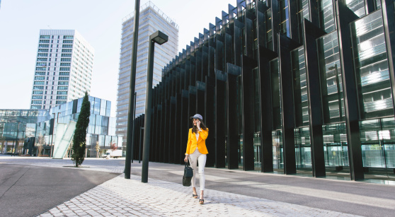 Spain, Catalunya, Barcelona, young woman with yellow jacket on the move in the business district
